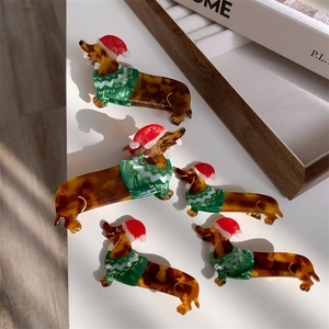 Close-up of dachshund acetate hair clips with festive red Christmas hats and green sweaters