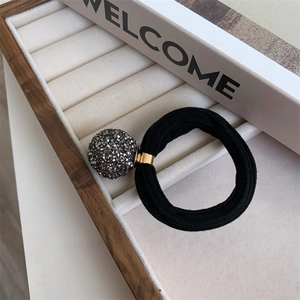 Detail of high-elastic black hair tie with dark grey rhinestone ball and gold metal clasp
