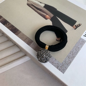 Detail shot of a grey rhinestone ball charm on high elasticity black hair tie strap