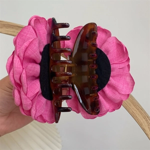 Detail of a large pink fabric rose hair claw clip with brown tortoiseshell texture finish