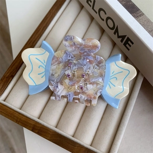 Detail view of acetate claw clip with marble texture, rhinestones and blue accents