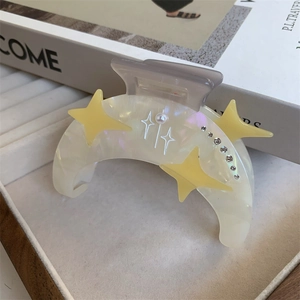 Détail d'une pince à cheveux lune en acétate ornée de perles et de strass en étoile
