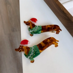 Close-up of a pair of dachshund hair clips with festive Christmas hats and green sweaters
