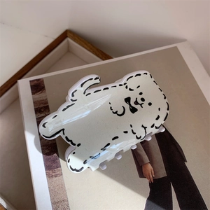 Détail d'une pince à cheveux en acrylique crème motif chien sur un magazine de mode