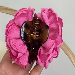 Detail shot of large pink fabric flower hair claw clip with tortoise resin base