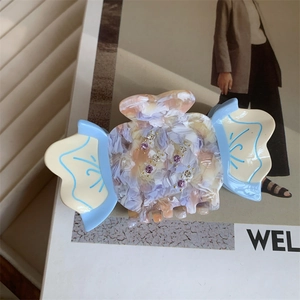 Detailed view of acetate hair claw clip with colorful marble texture and inlaid rhinestones