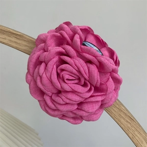 Detailed macro view of magenta fabric flower hair claw with linen texture on a wooden stand