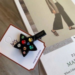 Détail d'une pince à cheveux en forme d'étoile avec strass colorés sur carte de vente