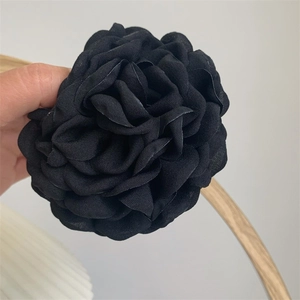 Detail view of a handcrafted black fabric camellia hair claw clip made of organza