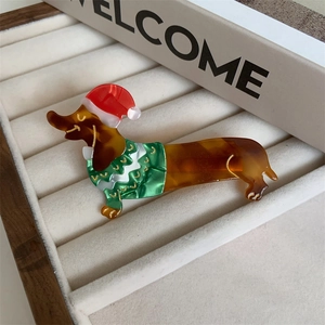 Detail of dachshund hair clip with red Santa hat and green sweater in jewelry box