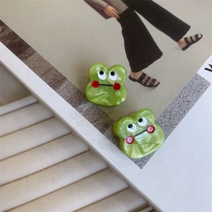 Close-up of green frog hair clips with marble texture and cute 3D eyes for styling