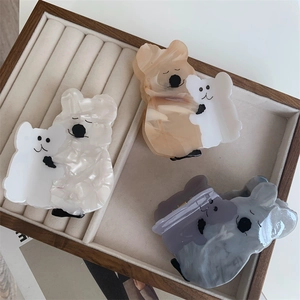Trois pinces à cheveux koala en acétate blanc et gris marbré sur un plateau à bijoux