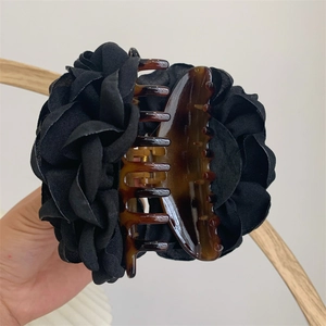 Detail of a large brown tortoiseshell hair claw with elegant black 3D fabric flower accents