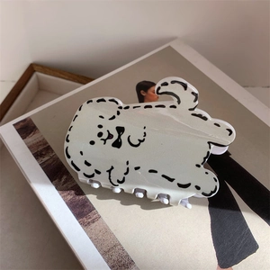Détail d'une pince à cheveux mignonne en résine en forme de chiot blanc sur magazine