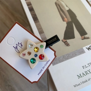 Détail macro d'une barrette étoile avec strass colorés sur une base pentagramme crème