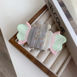Detailed view of a candy-shaped acetate hair claw clip with rhinestones on a jewelry tray