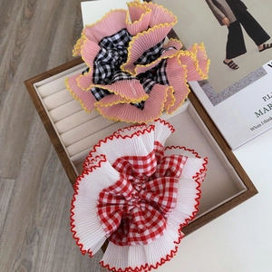 Close-up of pink and white lace scrunchies with plaid patterns on a wooden jewelry tray