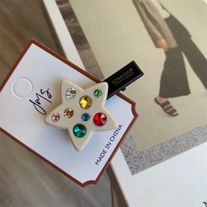 Détail d'une pince à cheveux en étoile avec des strass multicolores sur une base blanche