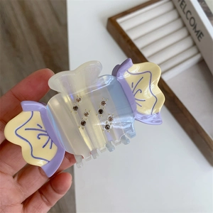 Close-up of candy-shaped acetate hair claw with rhinestones and iridescent finish