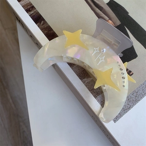Détail de la pince à cheveux lune en acétate avec perles irisées, étoiles et cristaux