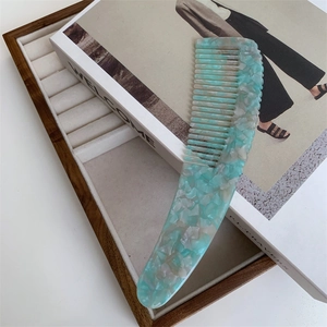 Detailed macro view of wide-tooth acetate comb with mint green marble texture on an art book