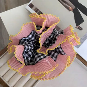 Close-up of pink scrunchie with lace edges and plaid pattern on a velvet jewelry box