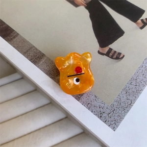 Detail of cute orange acetate monster hair claw clip on fashion magazine page