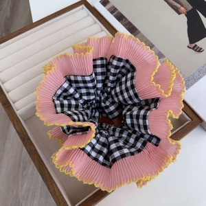 Detailed view of pink pleated organza and black checkered fabric scrunchie in a box