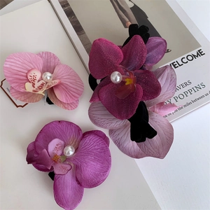 Detailed close-up of cloth orchid hair clips with realistic texture and pearl centers