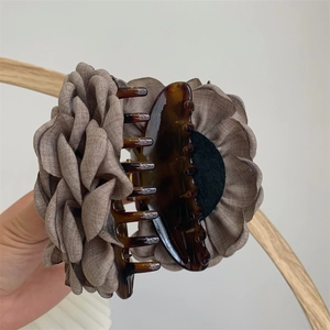 Close-up of a large brown fabric floral hair claw clip with tortoise shell acrylic base