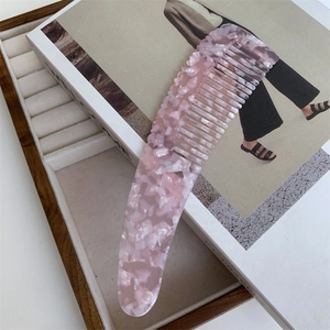 Detailed macro view of pink marble acetate hair comb with smooth teeth on book
