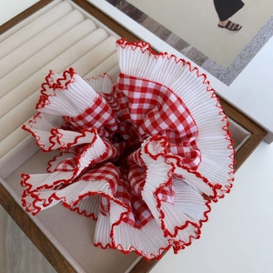 Detailed view of red and white gingham scrunchie with layered ruffle lace edges