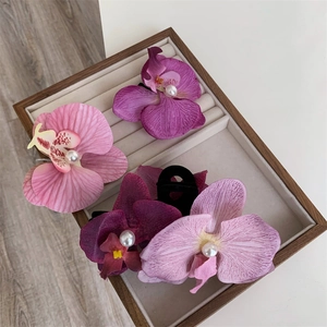 Close-up of four Phalaenopsis orchid hair clips with pearls in a wooden jewelry box
