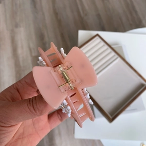 Détails de la pince à cheveux en acrylique rose avec fleurs blanches et strass brillants