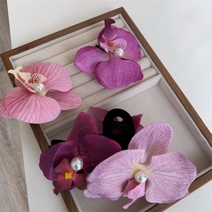 Detailed view of four orchid hair clips with realistic fabric petals and white pearls