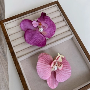 Detailed view of orchid hair clips in purple and pink with pearls on velvet display tray