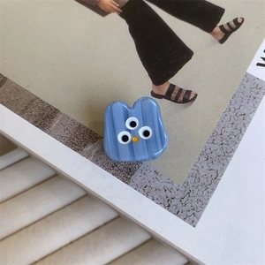 Close-up of blue three-eyed monster acetate hair claw clip with striped texture details