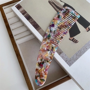 Detail of a thick acetate hair comb with colorful marble texture and ergonomic long handle
