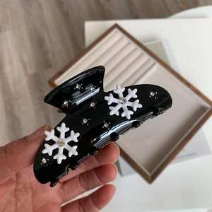 Gros plan sur une pince à cheveux noire avec motifs flocons de neige et strass brillants