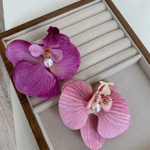 Detailed macro view of orchid hair clips with realistic fabric petals and center pearls
