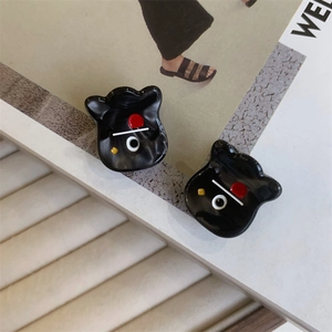 Detail of quirky black acetate monster claw clips with red accents and glossy finish