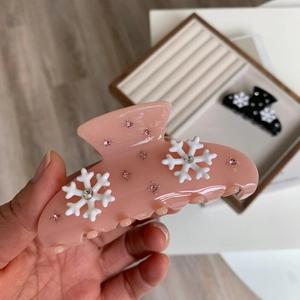 Gros plan d'une pince à cheveux rose avec flocon de neige et strass sur plateau