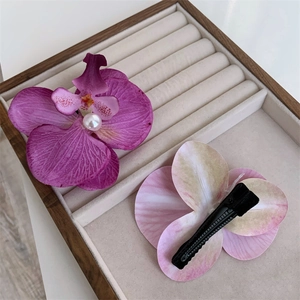 Detail view of purple orchid hair clip with pearl center and black metal duckbill clip