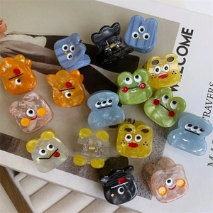 Close-up of colorful monster acetate hair claws with funny cartoon eyes on fashion book