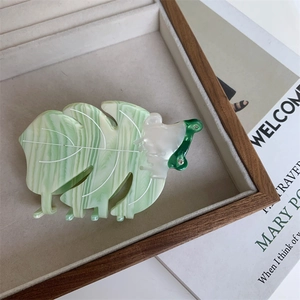Détail d'une pince à cheveux motif marbre vert avec un design de feuille tropicale