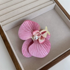 Close-up of pink orchid hair clip with silk petals and a central white pearl detail
