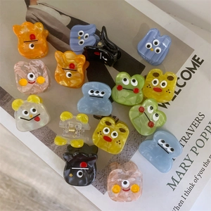 Detail showing colorful acetate hair claws with cartoon faces on a magazine
