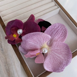 Detail view of purple orchid hair ties with realistic fabric petals and pearl centers