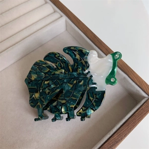 Vue détaillée d'une pince à cheveux feuille en acétate vert avec perles et strass