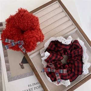 Detail of red fleece and plaid scrunchies with white lace edges on a tray